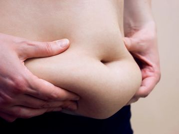 A person squeezing their belly fat.