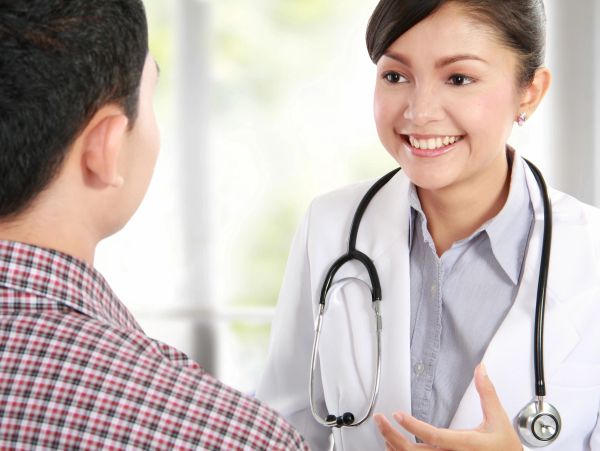 A female doctor smiling and talking to a male patient.