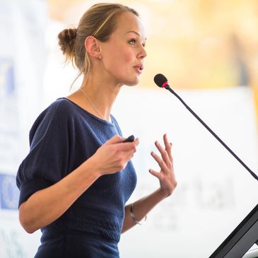 Young businesswoman behind lectern conducts presentation with confidence gained from media training