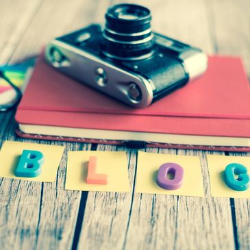 a camera on top of a book with the word BLOG spelled out in toy letters