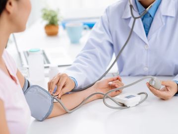 Doctor measuring patient's blood pressure with a cuff.