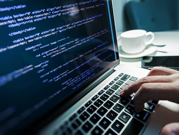 Person coding on a laptop with coffee nearby.
