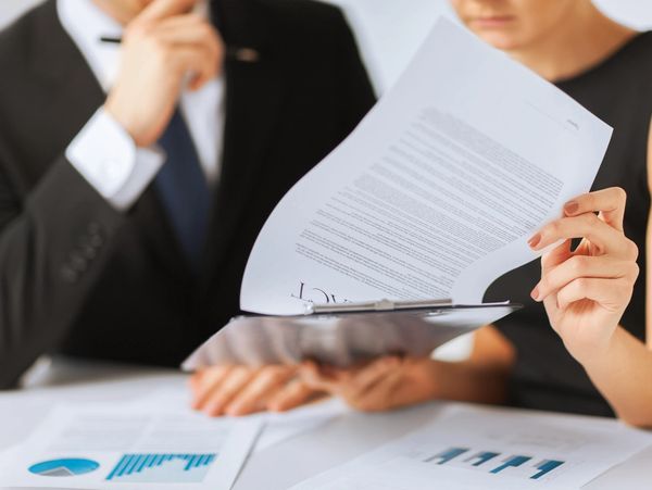 Two professionals reviewing documents and financial charts during a meeting.