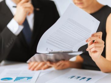 Two professionals review a contract document during a business meeting.