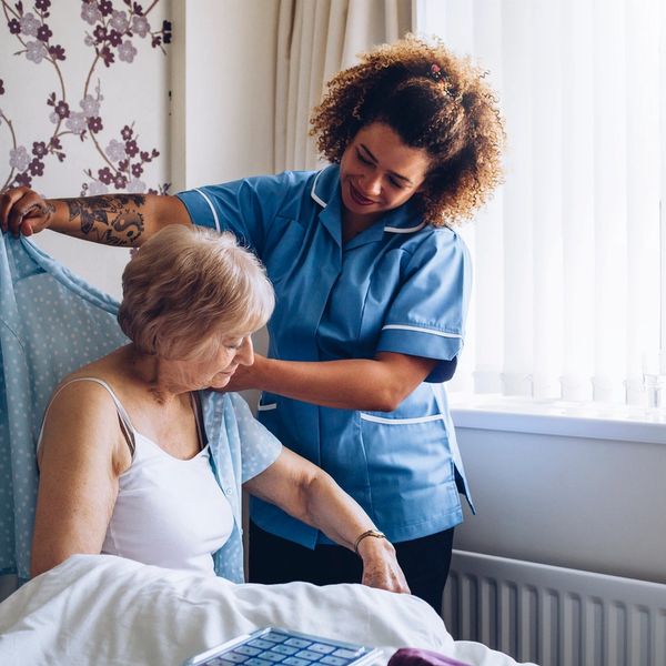 Nurse assisting an elderly client with daily activities in her home