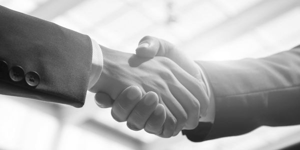 Two people shaking hands in business attire, symbolizing agreement.
