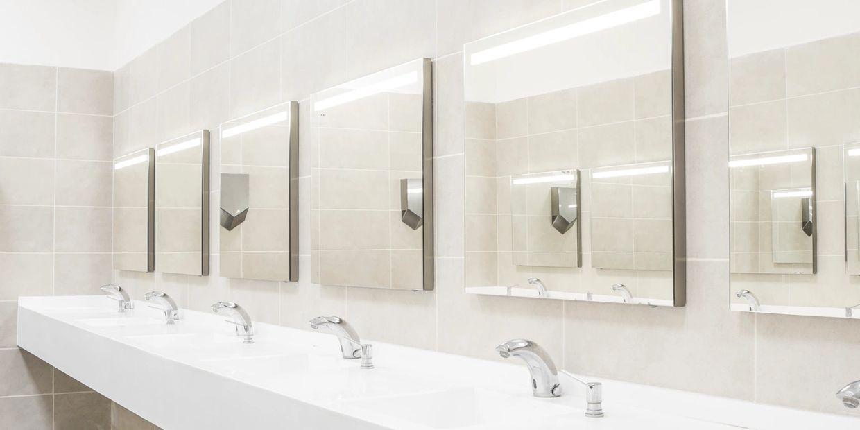 Image of a long sink with several mirrors above it.