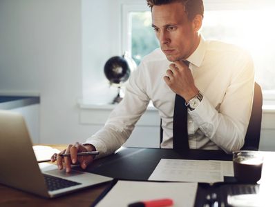 Businessman working intensely on laptop at office desk.