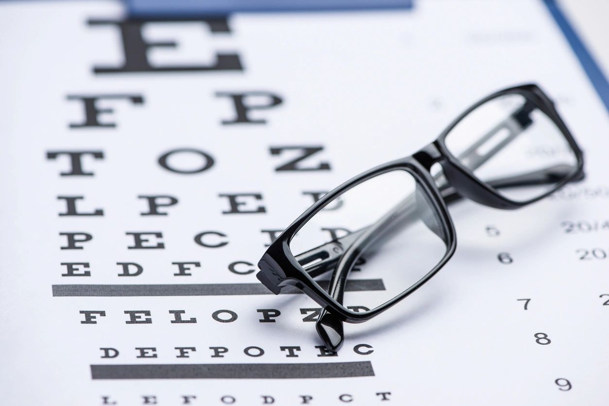 Black eyeglasses on an eye test chart.