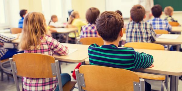 Students seated at desks in a traditional classroom.