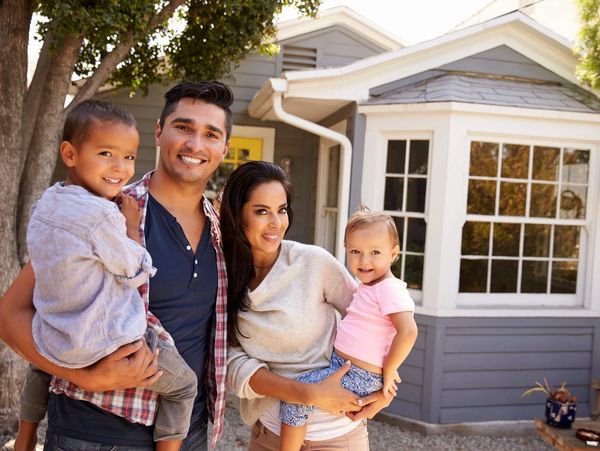 Family with children standing in front of house