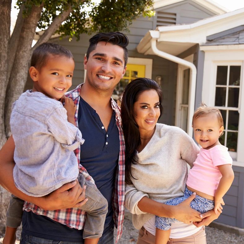 a family with young children stands in front of a house