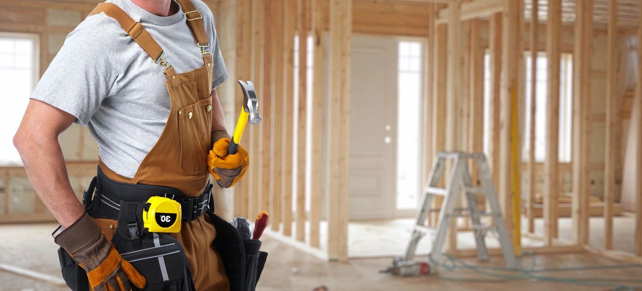 A contractor starts his day on the job site with hammer in his hand and his toolbelt on.