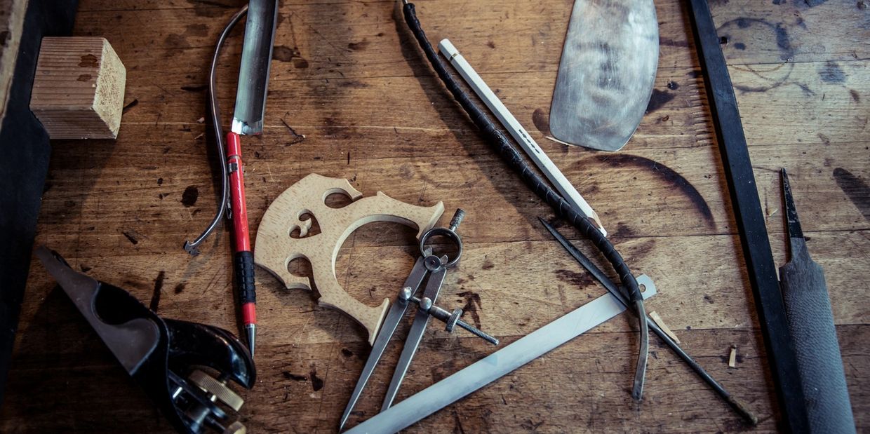Various woodworking and drafting tools on a worn wooden workbench.