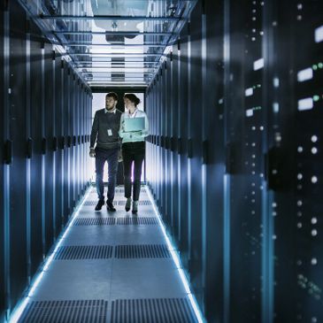 Duas pessoas a caminhar num corredor de um datacenter entre bastidores de servidores