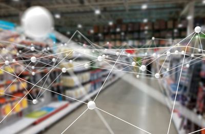 Network connections overlay in a blurred supermarket aisle.