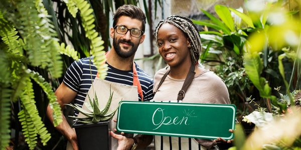 A man and woman holding plants in their hands.
