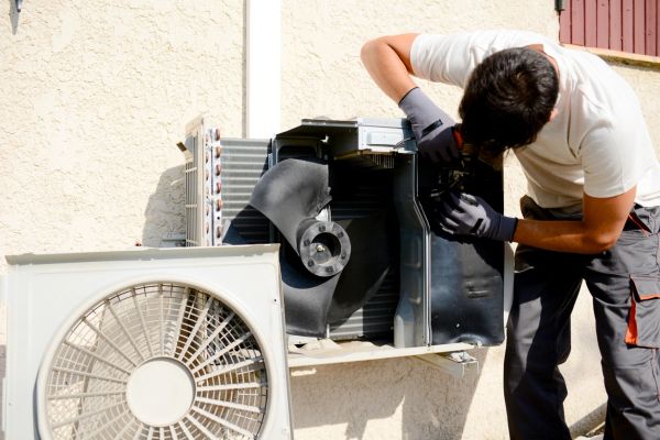 Technician repairing an outdoor air conditioning unit.