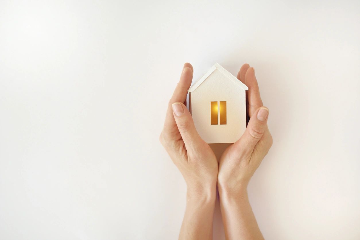 A model of a home being held in the palm of two hands.