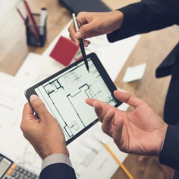 A man pointing a stylus at a tablet displaying a floor plan.