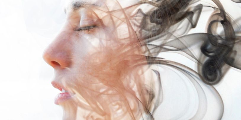 Profile of a woman blended with swirling smoke.