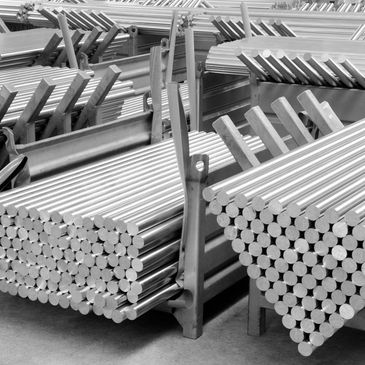 Stacks of shiny metal rods neatly arranged on racks in a warehouse.