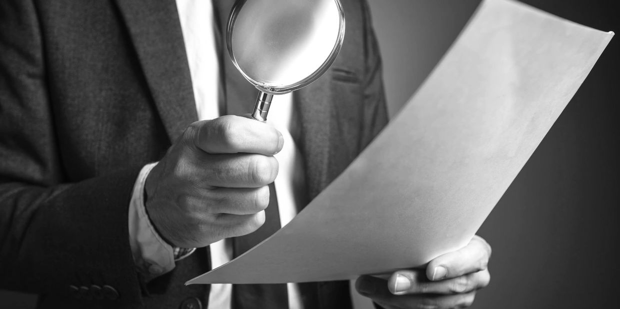 Historical firearms researcher examining WWII weapon shipping documents with a magnifying glass.