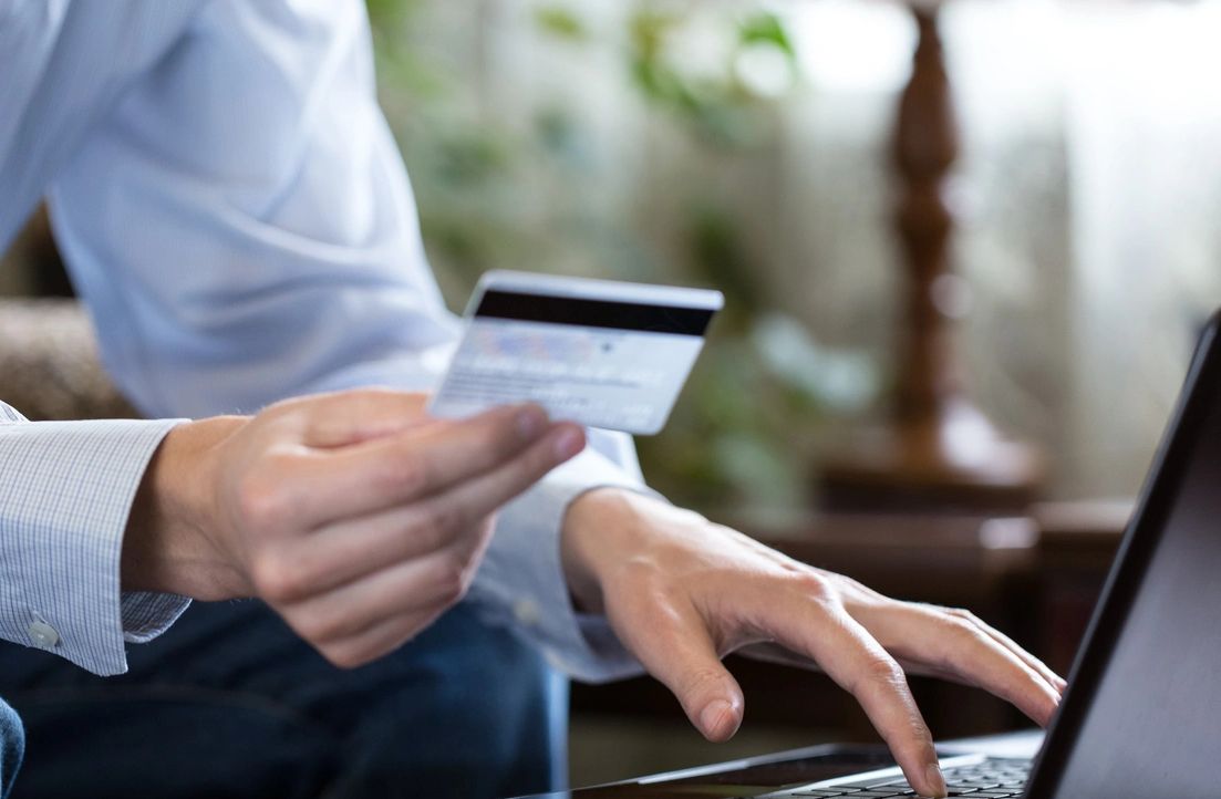 Man hold the credit card on our hand with typing keyboard on the laptop