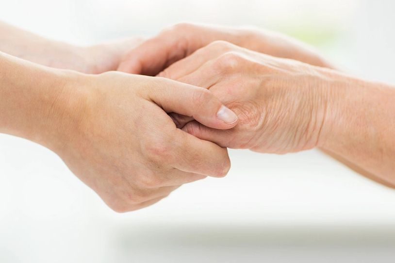 Caregiver holding a senior person’s hand with compassion and support.