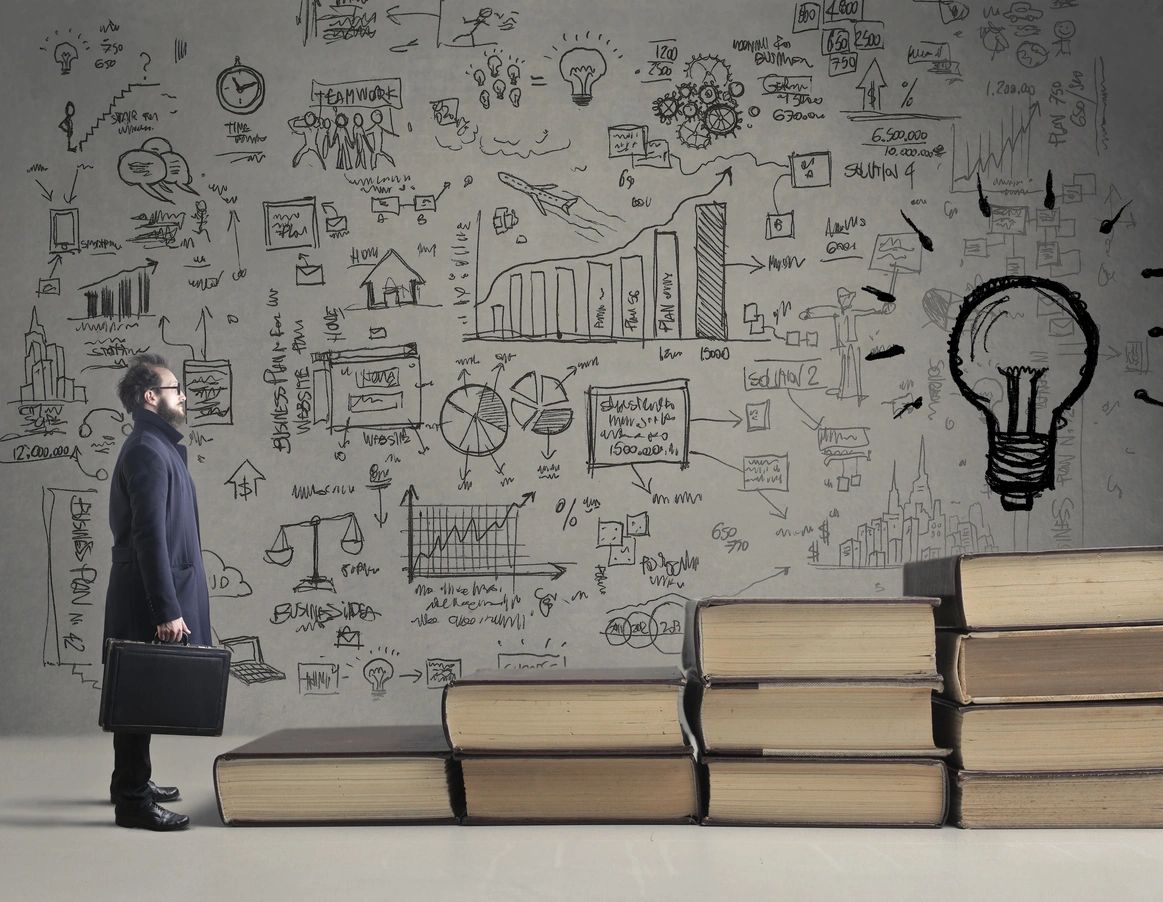 Man in trench coat with his briefcase approaches a staircase of books with several ideas on the wall's backdrop.