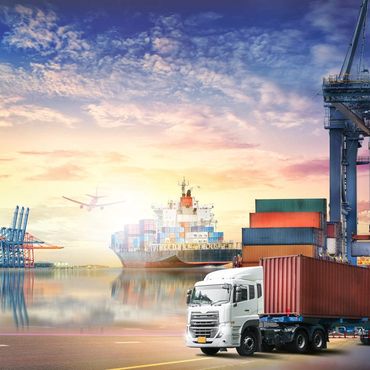 Cargo truck and ship at a busy port during sunset.