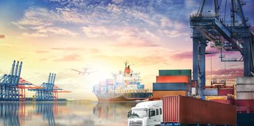 A busy shipping port with containers, a cargo ship, truck, and airplane at sunset.