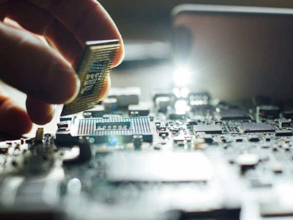 Hand installing a microchip on a circuit board.