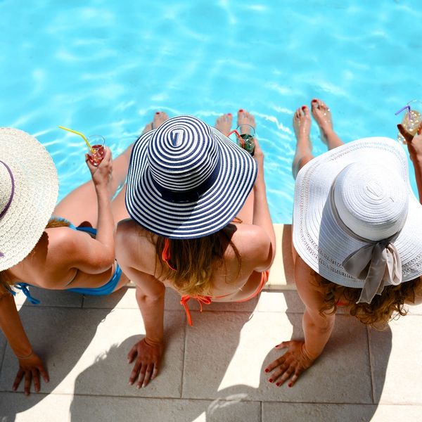 Three women sitting by the pool with beach hats