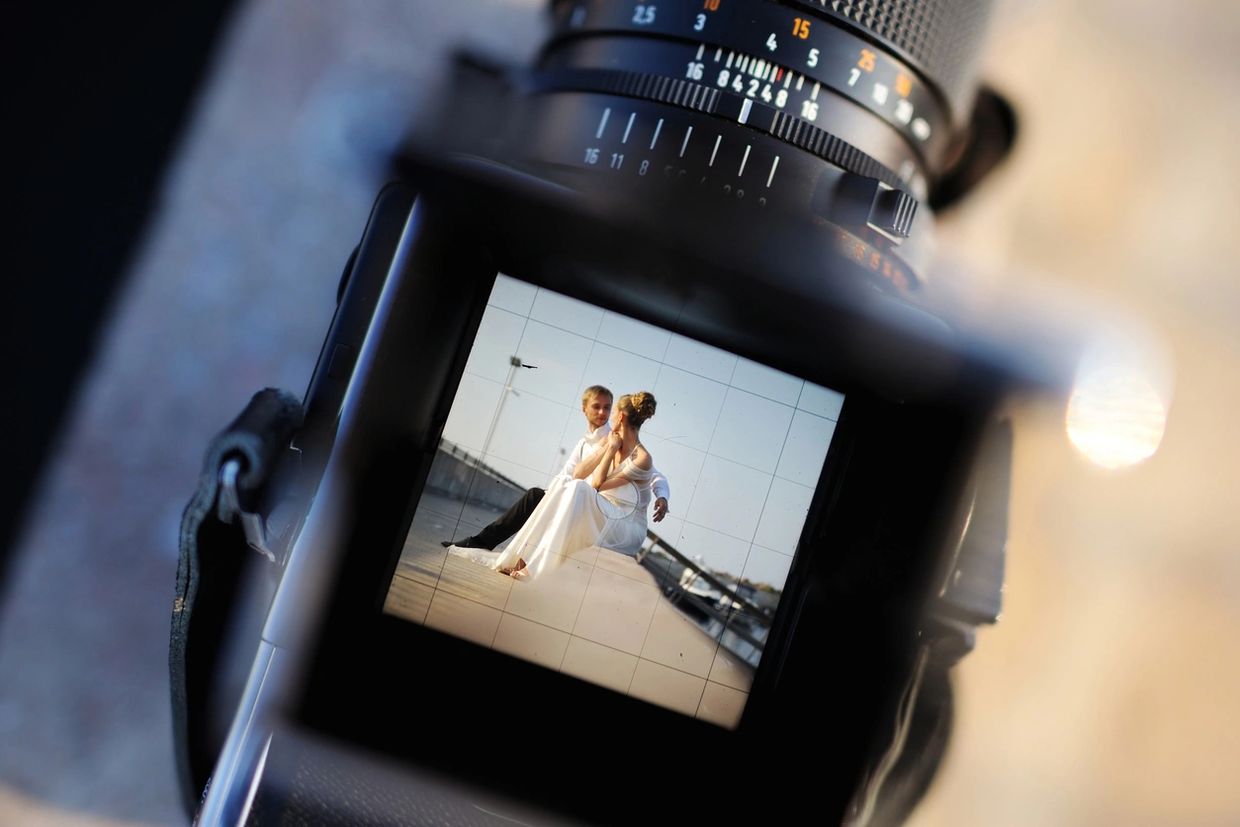 Couple in wedding attire captured through a camera viewfinder.
