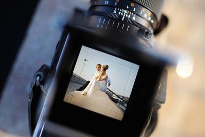 Photo of a bride and groom captured through a camera viewfinder.