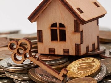 small Wooden house and key sitting on coins. Click here for specific account info