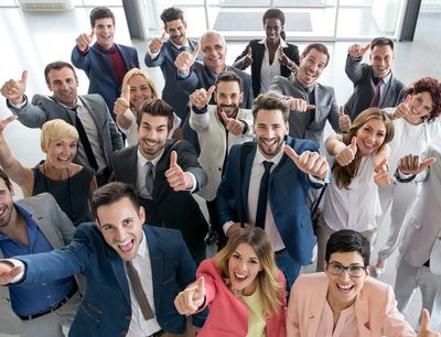 A diverse group of professionals giving thumbs up and smiling.