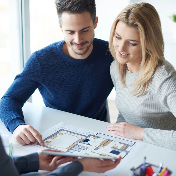 A couple looking on house construction plans with a real estate agent