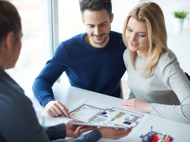 Couple reviewing a house floor plan with an agent.