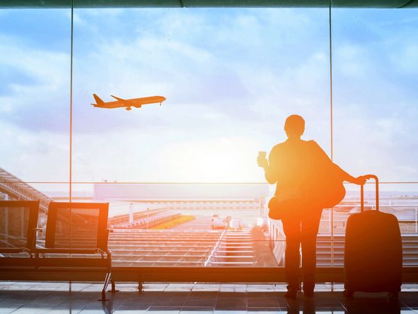 A woman gazing out the airport window, dreaming of her upcoming adventure.