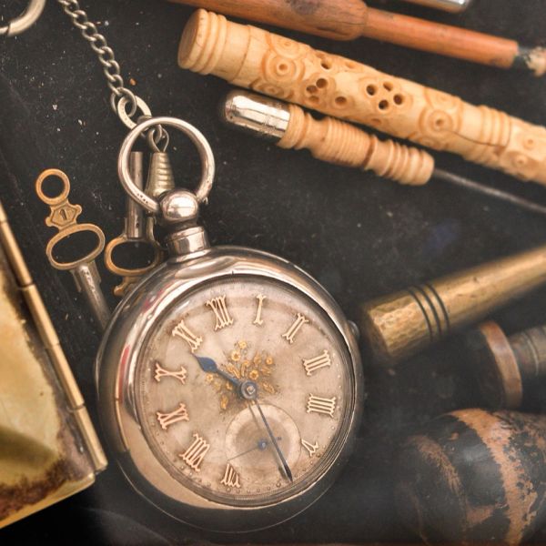 Vintage pocket watch surrounded by old musical instruments and keys.