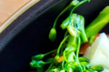 Close-up of fresh green broccolini in a black bowl.
