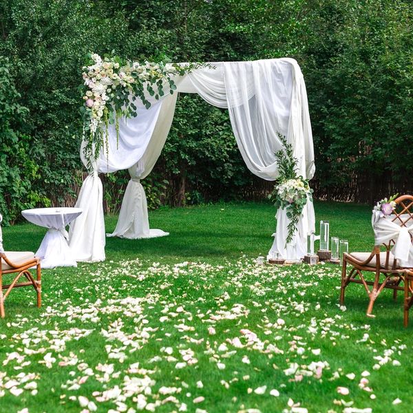 Wedding arch with draping at lovely outdoor wedding with flower petals in the aisle.  