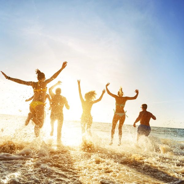 Group of people running in to the ocean.