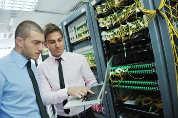 professionals viewing laptop in network room