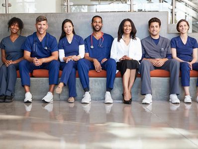 A picture of different healthcare workers sitting in a row in a hospital type setting.