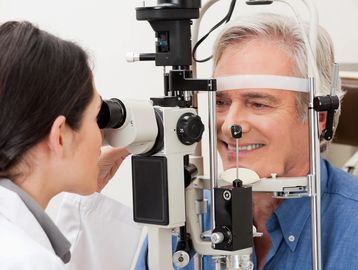 Eye examination being conducted by an optometrist on an elderly man.