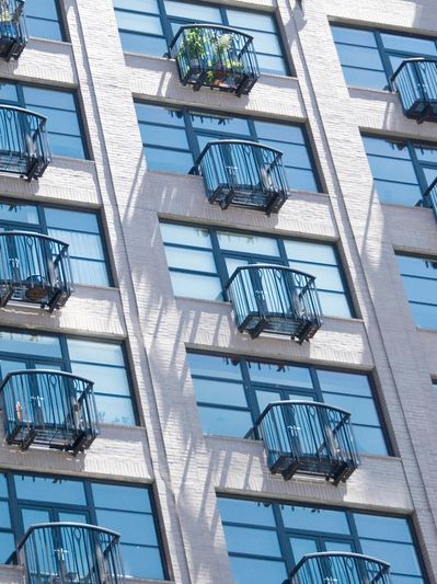 Modern building facade with small curved balconies and large windows.