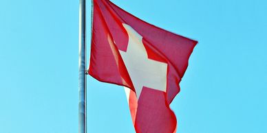 Swiss flag flying with blue skies behind